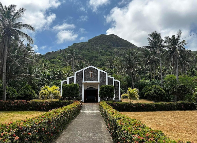 A church with a cross, surrounded by palm trees and a mountain. 2