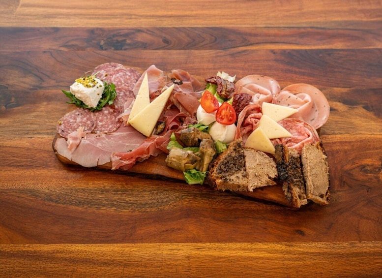 A charcuterie board with various meats, cheeses, and vegetables on a wooden table. 4