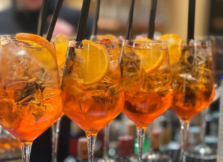 A row of glasses with orange slices and ice cubes. 2