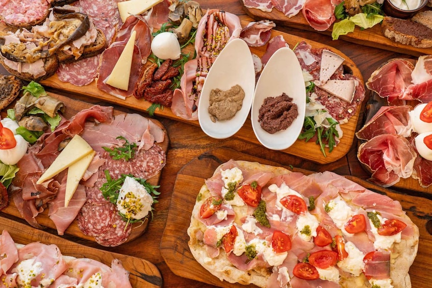 An assortment of cured meats, cheeses, and vegetables on wooden boards. 5