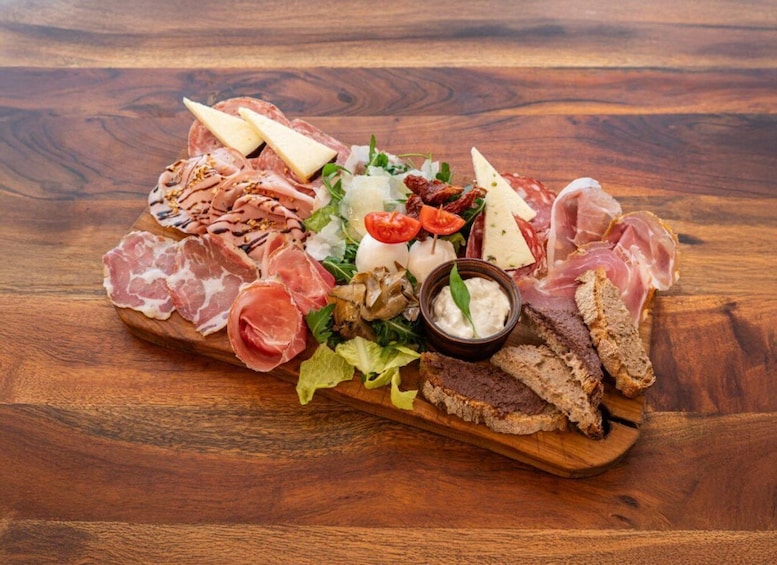 A charcuterie board with various meats, cheeses, and bread on a wooden table. 3