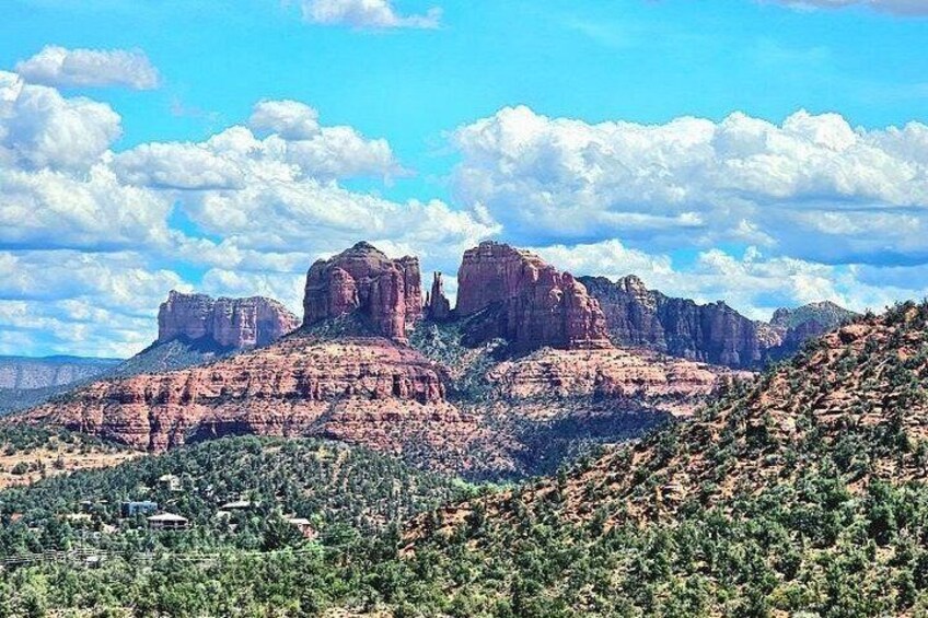 A mountainous landscape with prominent red rock formations and green vegetation. 2