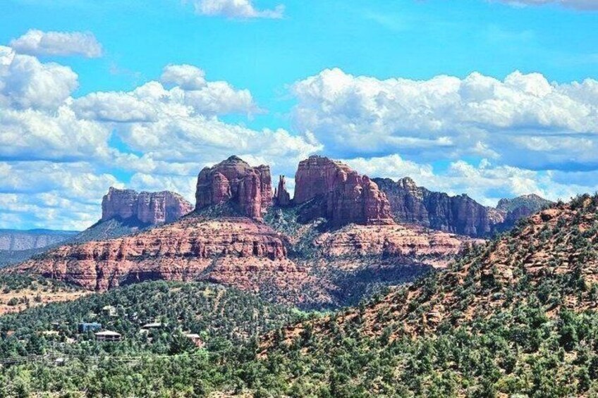 A desert landscape with prominent red rock formations and sparse green vegetation. 3