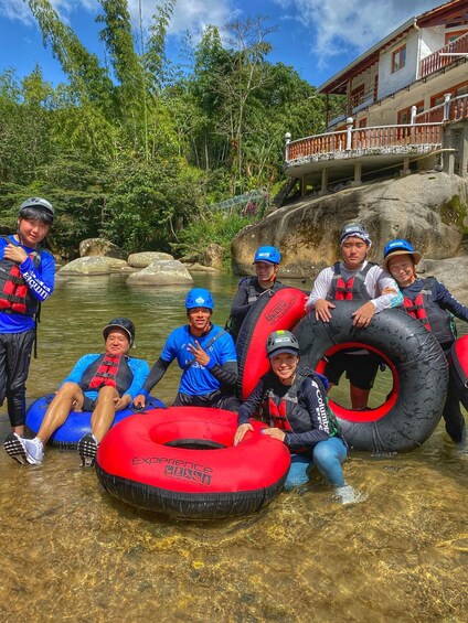 A group of people in a river wearing life jackets and helmets, holding inflatable tubes. 4