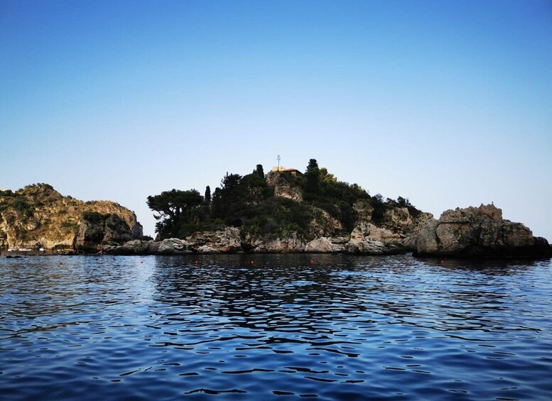 A rocky island with a small building and trees, surrounded by calm water. 5