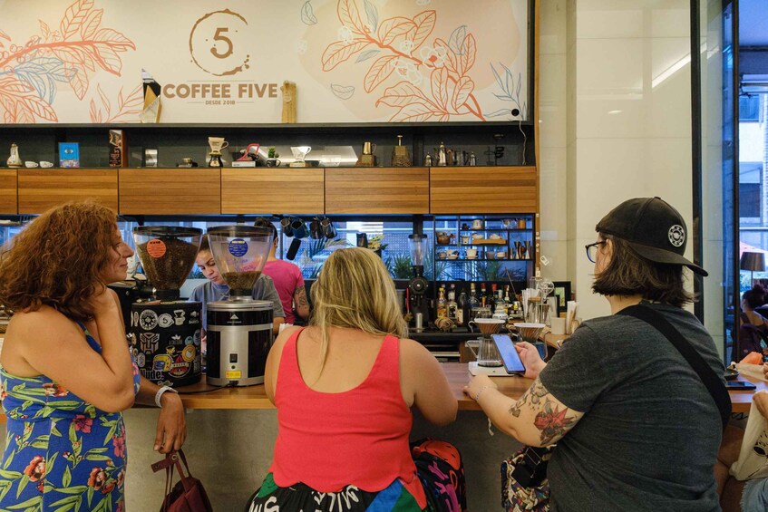 A coffee shop interior with a counter, coffee machines, and a wall with a coffee-related mural. 2