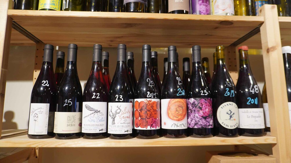 A wooden shelf with rows of wine bottles, each labeled with a number and year. 2