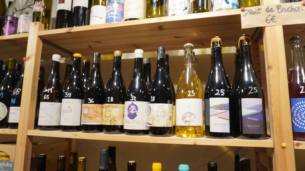 A variety of wine bottles on wooden shelves, some with price tags. 5