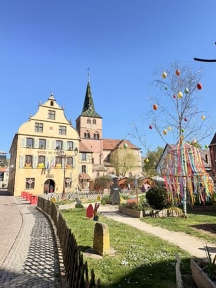 A historic building with a tower, a cobblestone path, and a decorated tree. 3