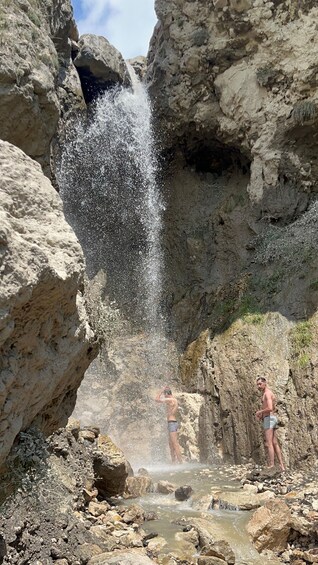 Une cascade dans un paysage rocheux, avec deux personnes debout à proximité. 5