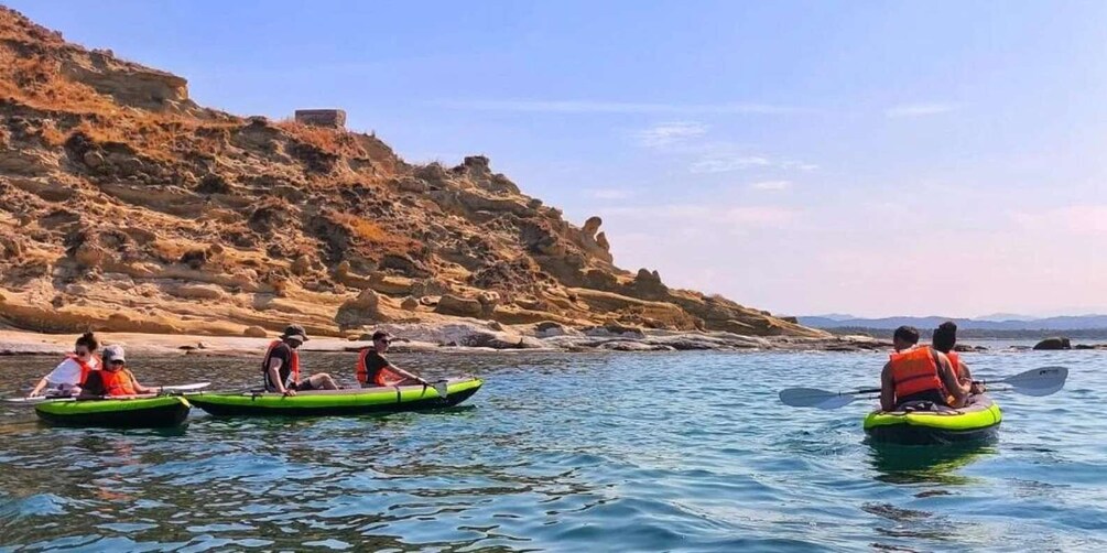 People kayaking on a calm river with rocky cliffs in the background. 1