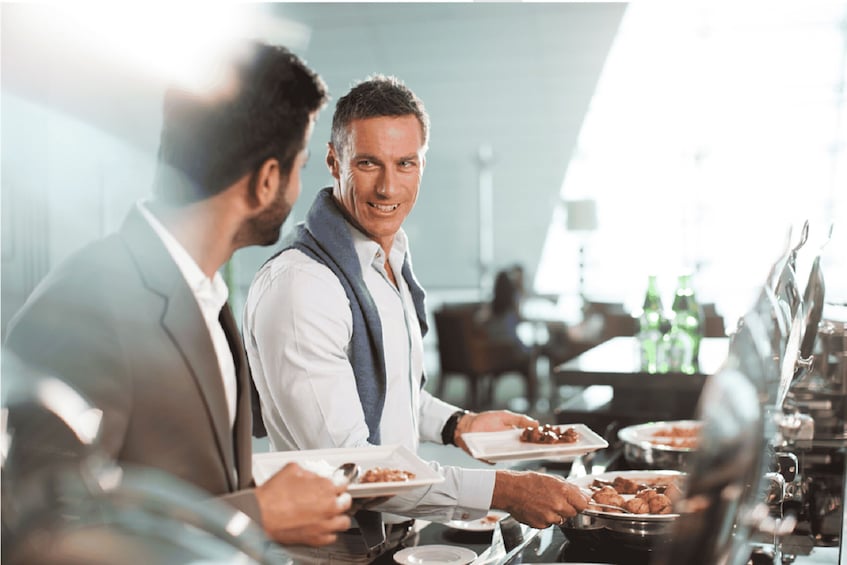 Two men in a cafe, one holding a plate of food. 5
