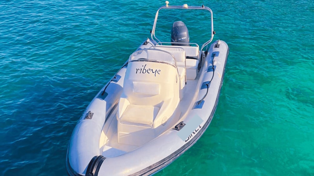 A small motorboat with the name 'ribene' on its side, floating on clear turquoise water. 4