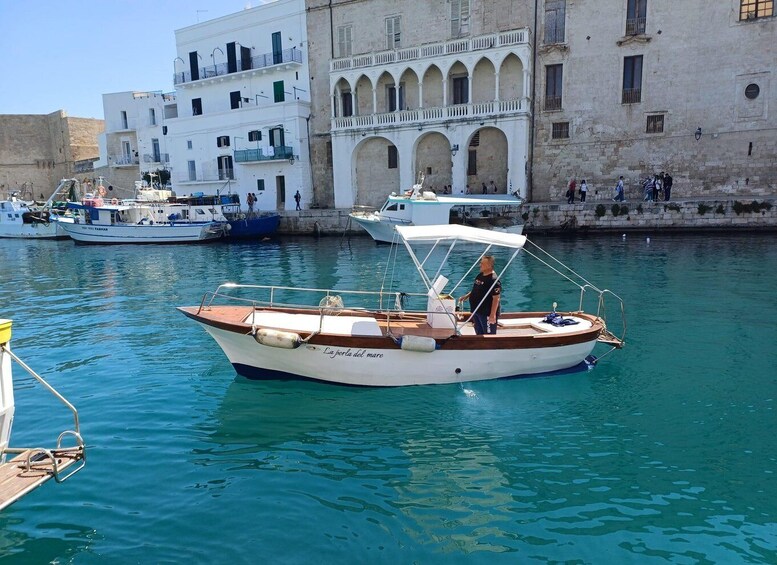 A small boat docked at a harbor with buildings in the background. 2