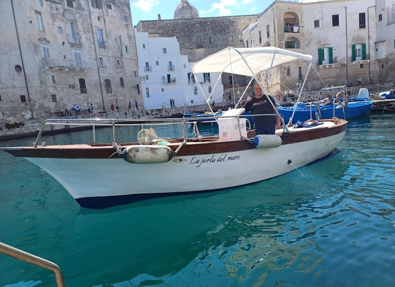 A boat named 'La perla del mare' docked in a harbor with historic buildings in the background. 3