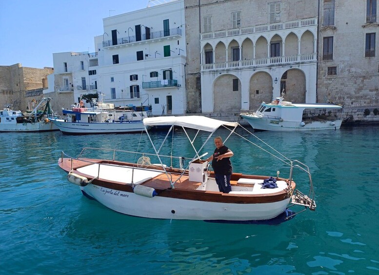 A small boat docked at a marina with buildings in the background. 1