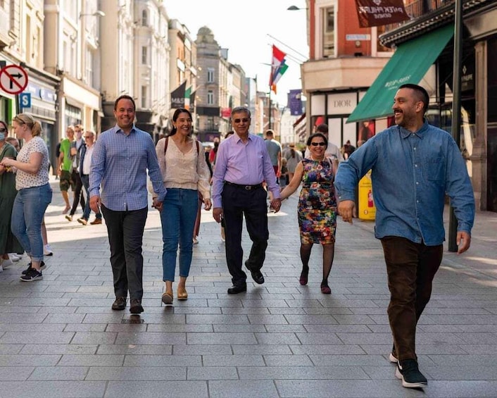 A group of people walking on a city street with shops and flags in the background. 4