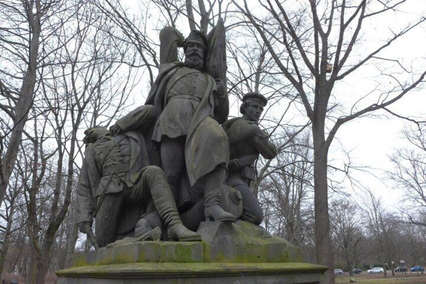 A statue of soldiers in a park with bare trees in the background. 3