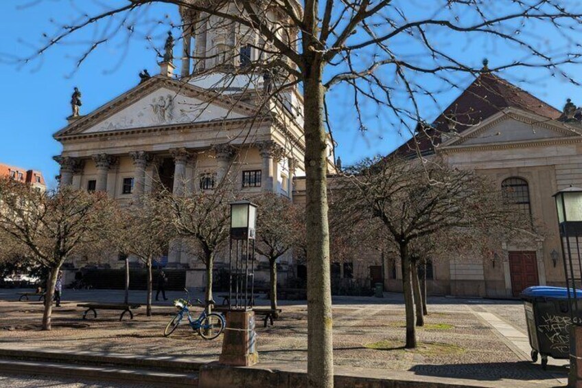A classical building with columns, a bicycle, and leafless trees. 4
