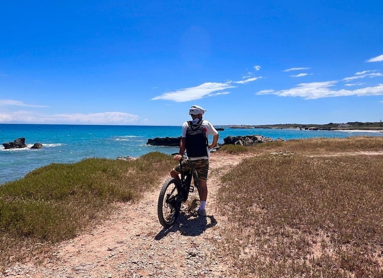 A person on a mountain bike on a dirt path by the sea. 1