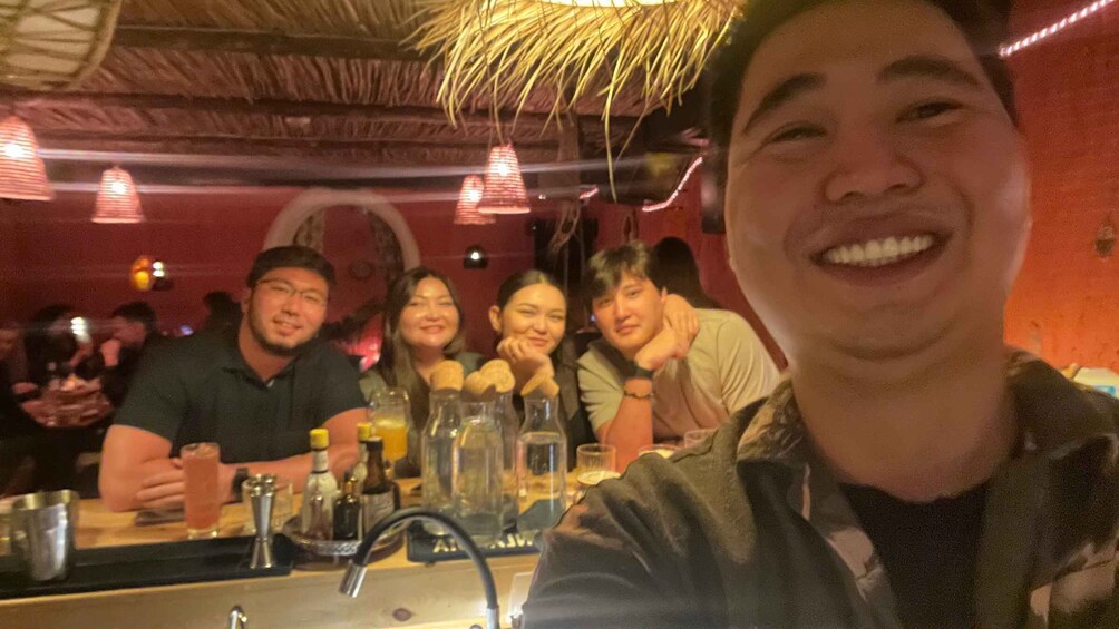 A group of people seated at a bar with drinks and glasses on the counter. 5