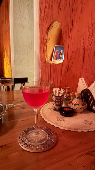 A table with a pink drink, a glass of water, and a photo frame. 1