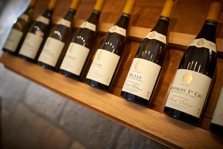 A row of wine bottles on a wooden shelf. 2