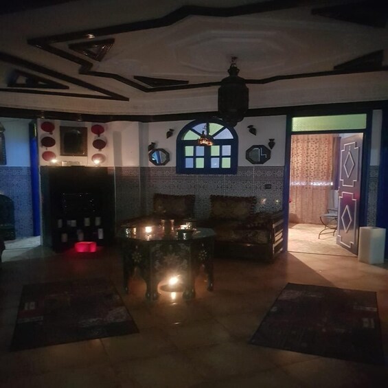 A dimly lit room with a patterned ceiling, a table with candles, and a patterned rug. 3