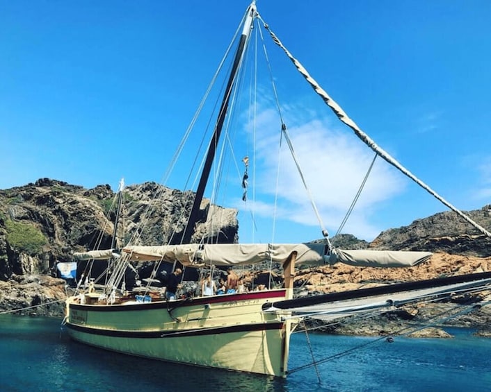 A traditional sailing boat anchored near rocky coast. 3