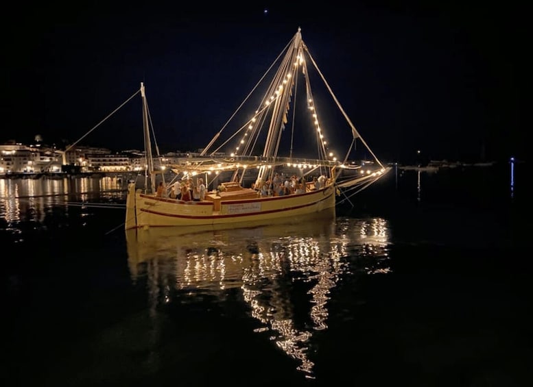 A lit fishing boat at night with city lights in the background. 2