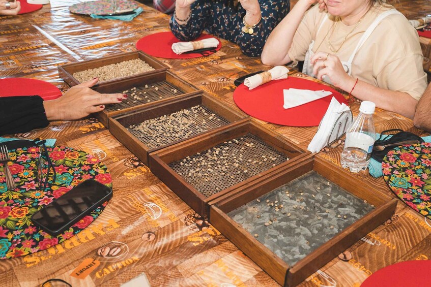 A group of people seated at a table with trays of nuts and a patterned tablecloth. 5