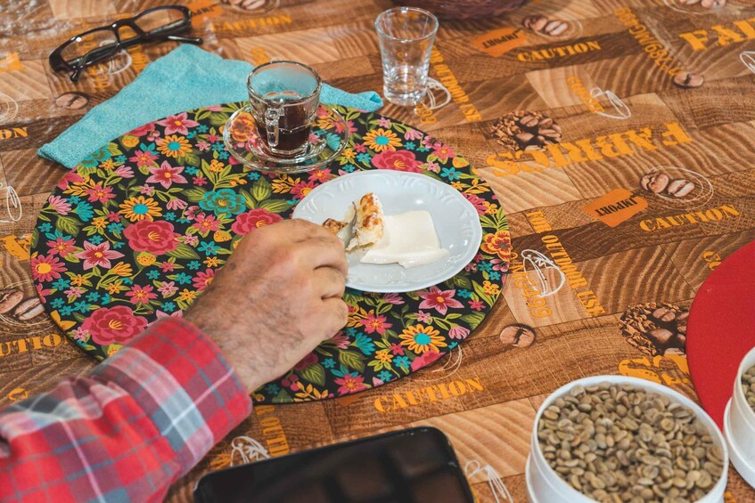 A person eating cheese with a napkin, a glass of water, and coffee beans on a table. 4