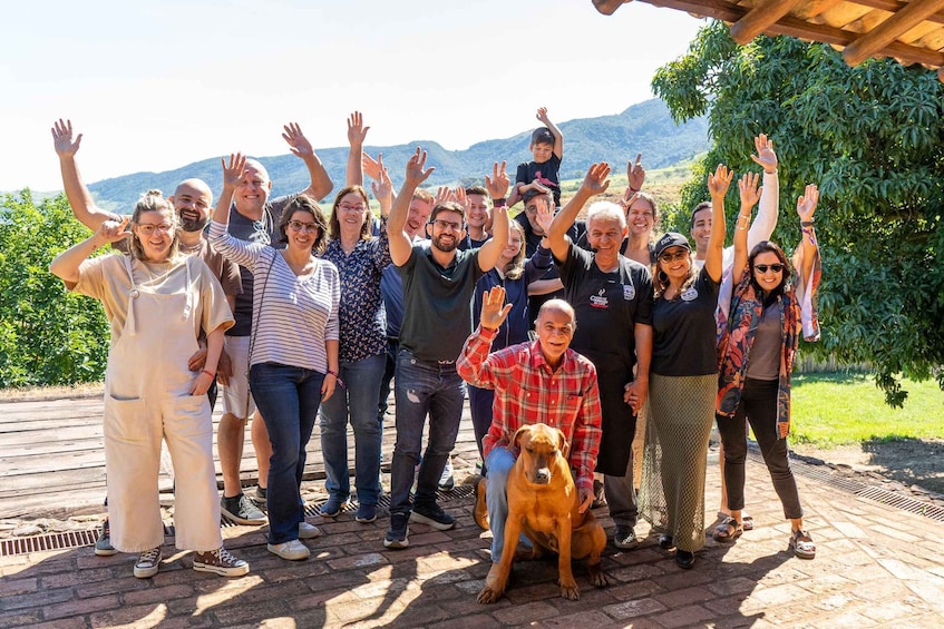 A group of people outdoors with a dog, raised hands, and a mountainous backdrop. 2