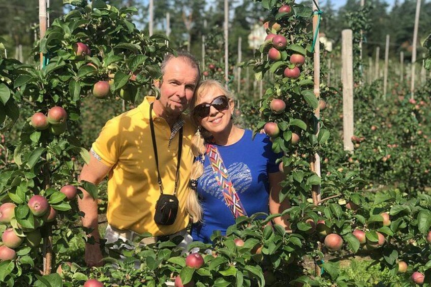 Twee personen staan in een boomgaard met appelbomen. 3