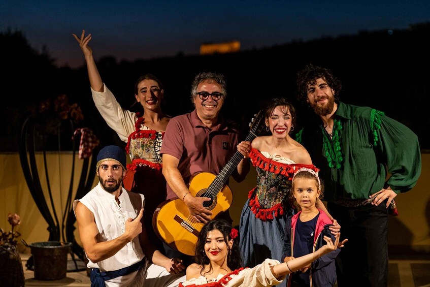 A group of people in traditional costumes with a guitar, posing for a photo. 4