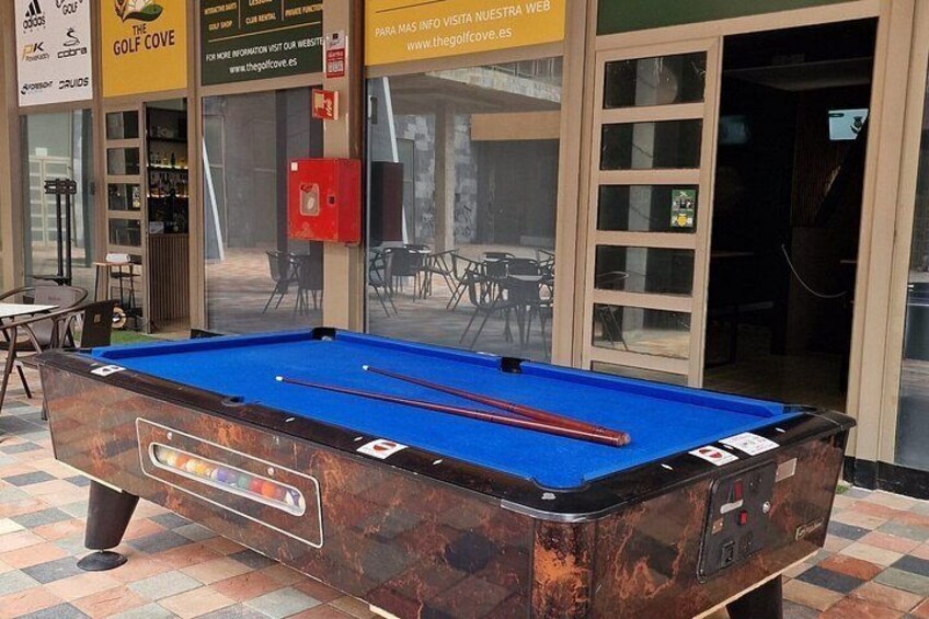 A pool table in an indoor setting with a red fire extinguisher and a door in the background. 2