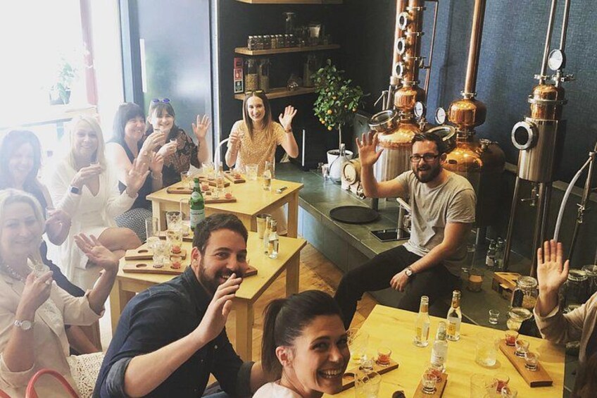 En grupp människor sitter vid bord i en restaurang, och i bakgrunden syns koppardestilleringsutrustning. 1