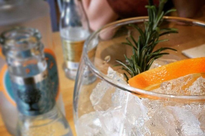 Ett glas med is, en skiva apelsin och en kvist rosmarin. 4