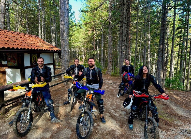 A group of mountain bikers in a forested area with a small building in the background. 3