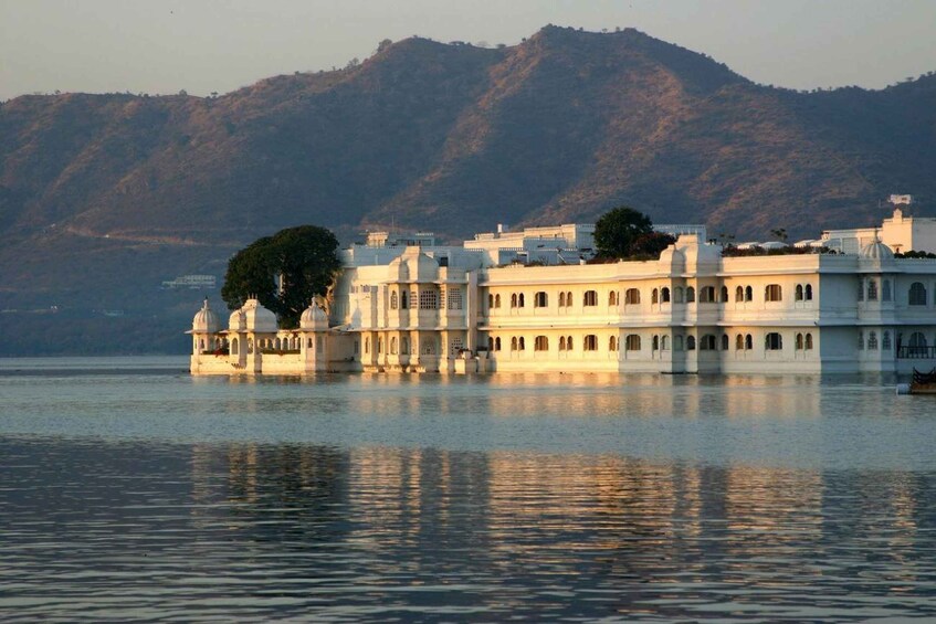 A lakeside palace with domed structures and a mountain backdrop. 1
