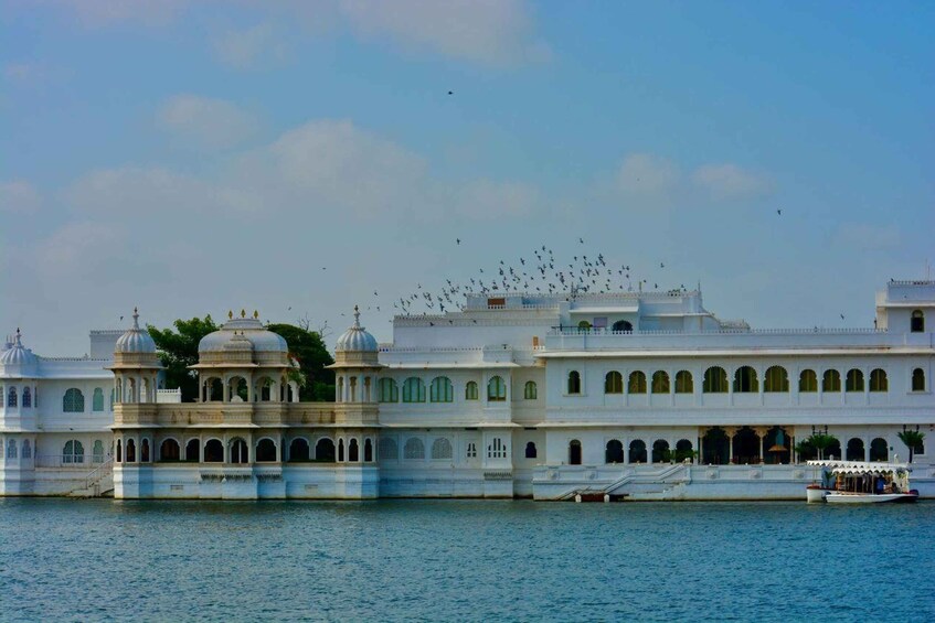 A white, multi-tiered building with domes and arched windows, situated by a body of water. 2