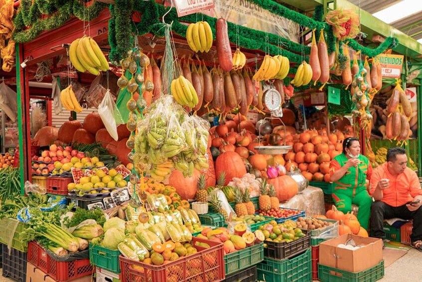 A vibrant outdoor market with fresh produce, including bananas, pumpkins, and pineapples. 1