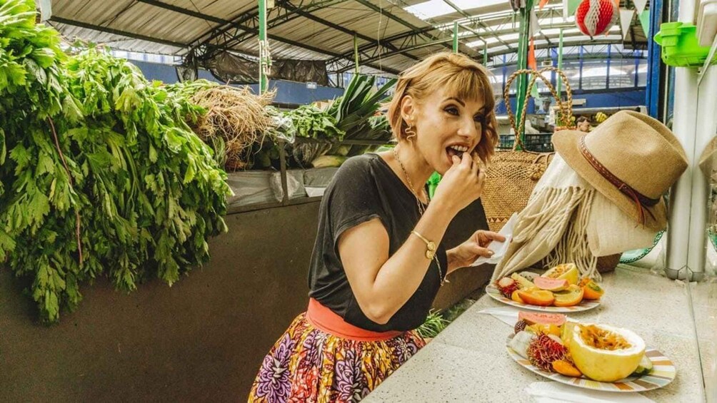 A person eating at a table with various fruits and vegetables. 5