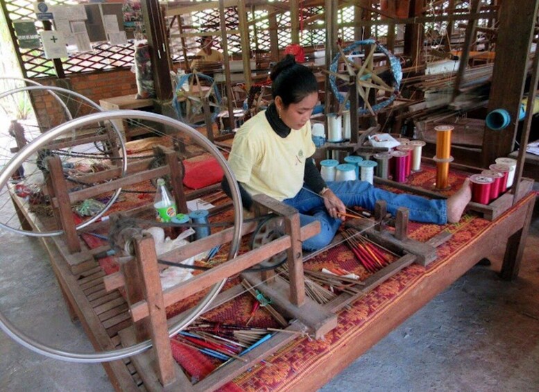 A person weaving on a traditional loom with spools of thread and wooden frames. 5