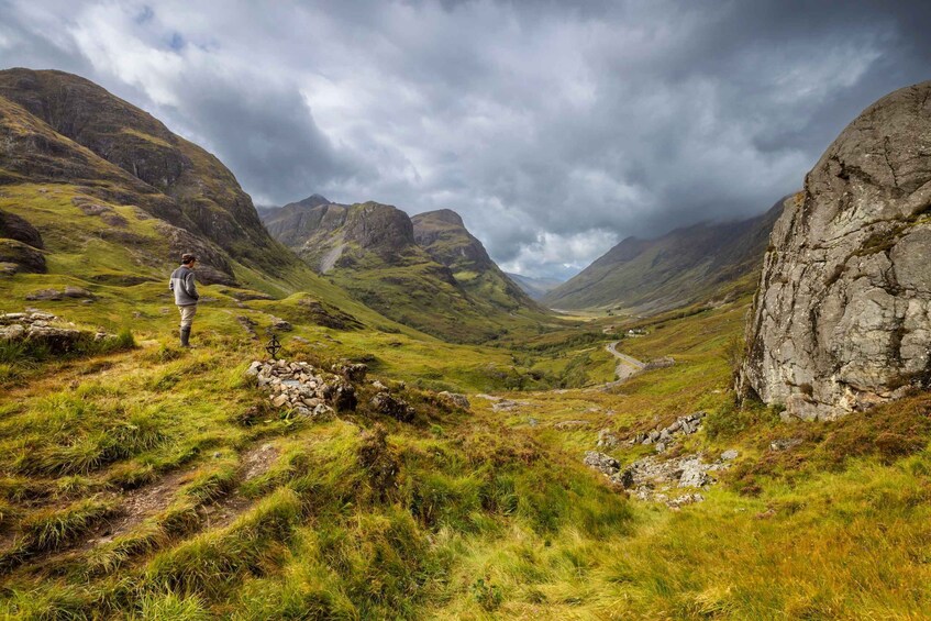 A hiker on a grassy path with mountains in the background. 5