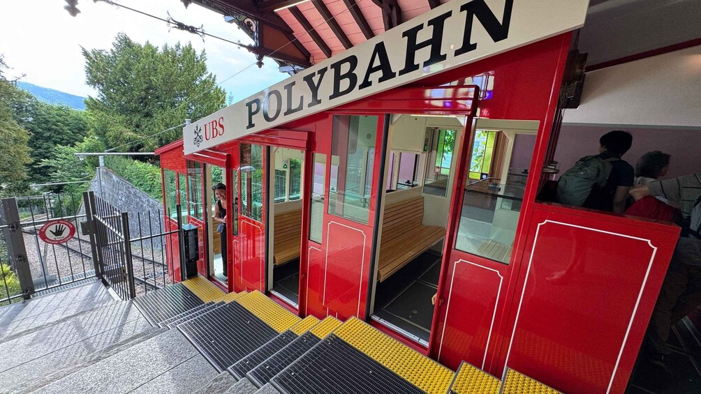 A red and white station named 'UBS POLYBAHN' with a person standing at the entrance. 5