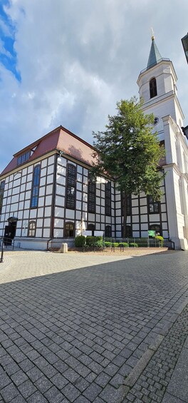A historic building with a clock tower and a large tree in front. 3
