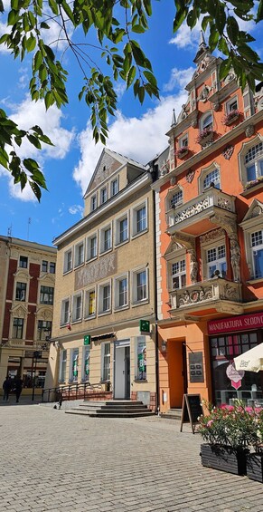 A cobblestone square with historic buildings, including a shop with a sign reading 'MANUFAKTURA SLODYC.' 4