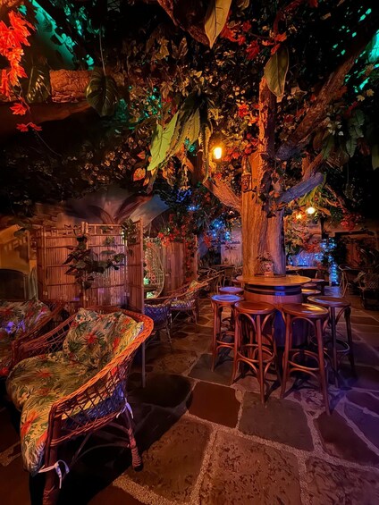 An indoor tropical-themed restaurant with wooden furniture and foliage decorations. 3