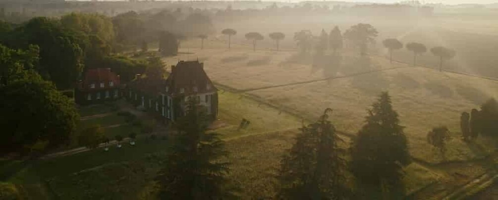 A rural landscape with a large house surrounded by fields and trees. 1